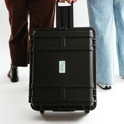 Two people pulling a hard-shelled protective case for Sayge with the Sayge logo on the front