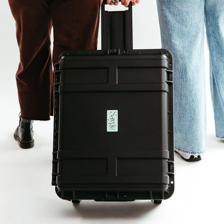 Two people pulling a hard-shelled protective case for Sayge with the Sayge logo on the front