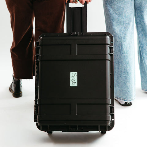 Two people pulling a hard-shelled protective case for Sayge with the Sayge logo on the front
